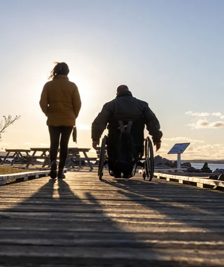 Person walking and person in wheelchar on dock
