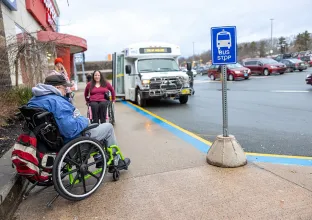 Two people in wheelchairs at bus stop