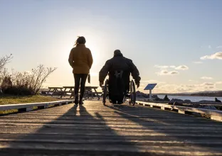 Person walking and person in wheelchar on dock