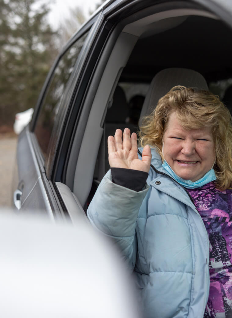 Woman waving from the passenger seat of a truck